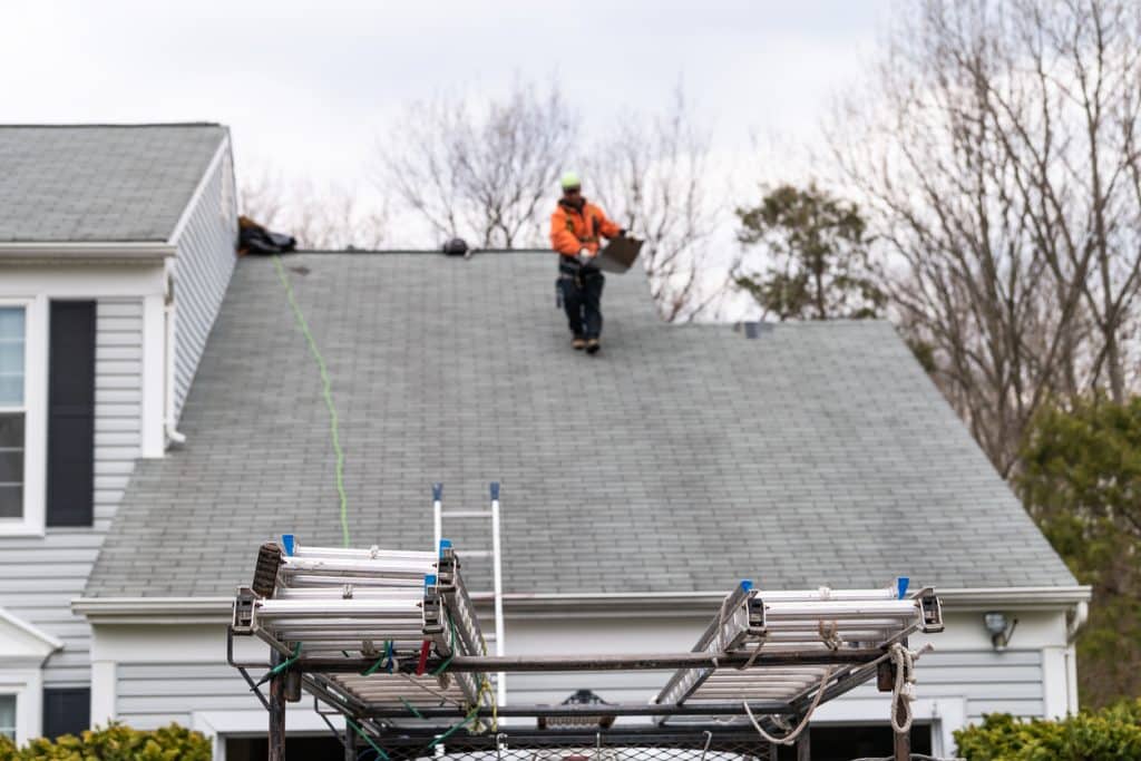 man walking on roof shingles